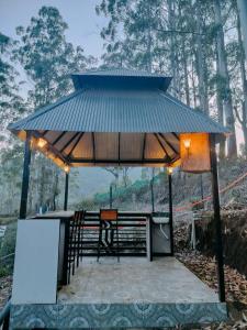 a pavilion with a table and chairs in a forest at Infinite Homestay in Kūkkāl