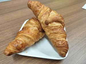 two croissants on a white plate on a table at Natural hot spring with sauna HOTEL GLAN Y's KOSHIGAYA in Koshigaya