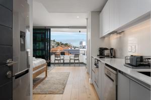 uma cozinha com armários brancos e vista para uma varanda em 7 on Bantry Apartments na Cidade do Cabo