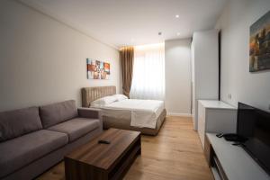 een woonkamer met een bank en een bed bij Tirana Elite Apartments in Tirana