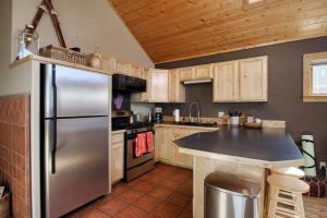 a kitchen with a stainless steel refrigerator and wooden cabinets at Little Lodge Leadville: charming 2bd in Leadville