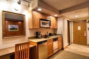 a small kitchen with wooden cabinets and a microwave at Studio at Perfect Location Unit 412 with Pool and Hot Tub in Crested Butte