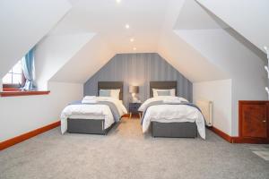 a attic bedroom with two beds with white sheets at Barraston Farm Country Retreat in Balmore