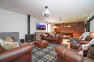 a living room with leather furniture and a fireplace at Barraston Farm Country Retreat in Balmore