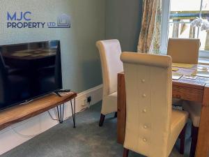 un soggiorno con tavolo, TV, tavolo e sedie di Cross Wynd view a Hawick