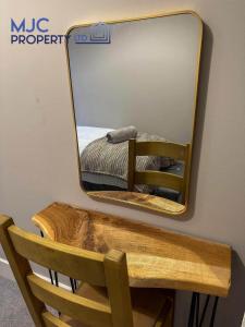 a mirror on a wall with a chair and a bed at Cross Wynd view in Hawick