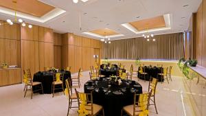 a banquet hall with black tables and yellow chairs at Click Hotel Biz, Bangalore International Airport in Yelahanka