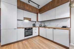 a kitchen with white cabinets and a wooden floor at RentPlanet - Apartament Międzynarodowa in Warsaw