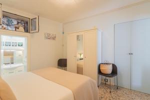 a white bedroom with a bed and a chair at Il Timone by Rent All Como in Colonno