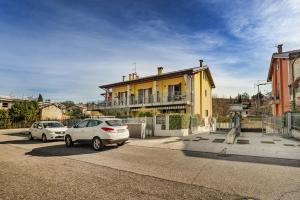 deux voitures garées devant une maison jaune dans l'établissement Dimora Santa Cristina Ceredello, à Caprino Veronese