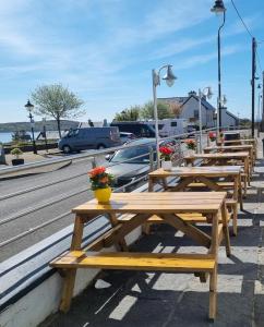 una fila de mesas de picnic de madera con flores. en Roundstone House Hotel en Roundstone