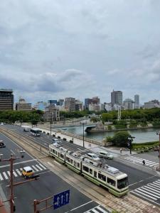 two trains on a street with a river and a city at bHOTEL Dai3Himawari - 30 sec to PeacePark!! HUGE comfort house Up to 10p in Hiroshima