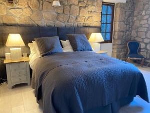 a bedroom with a blue bed with two tables and two lamps at Idyllic French farmhouse in Les Assions