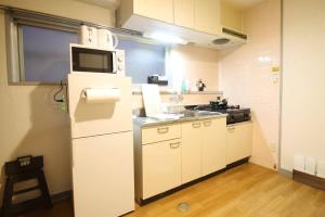 a small kitchen with a refrigerator and a sink at Earls Court - Capacious & Relaxing just 4 blocks to Peace Park in Hiroshima