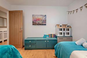 a bedroom with a blue dresser and a toy house at Oakwood Bungalow Christchurch Sleeps 8 in Iford