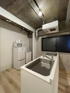 uma cozinha com um lavatório e um frigorífico em bHOTEL M's lea - 2BR Modern Apartment next to Peace Park 10 Ppl em Hiroshima