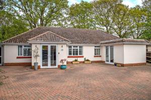 a white house with a brick driveway at Oakwood Bungalow Christchurch Sleeps 8 in Iford
