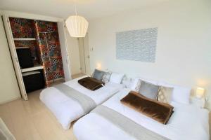 sala de estar con 2 camas y sofá en Luxes - 10 min Hiroshima Station & 2BR Up to 10p & 4 bikes, en Hiroshima