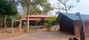 a building with a red roof in a park at The Heritage Home Stay in Mysore