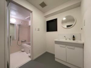 a bathroom with a sink and a toilet and a mirror at bHOTEL M's lea - Modern Spacious Apartment Beside Peace Park 10 ppl in Hiroshima