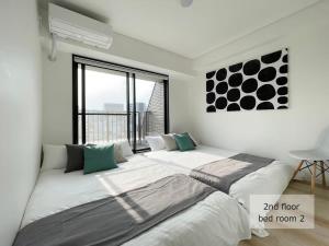 1 dormitorio con 1 cama grande y ventana grande en bHOTEL M's lea - Spacious 2 level apartment 4BR for 16 PPL, en Hiroshima