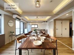 uma sala de jantar com uma longa mesa de madeira e cadeiras em bHOTEL M's lea - Spacious 2 level apartment 4BR for 16 PPL em Hiroshima