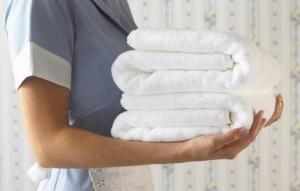 a woman holding a stack of white towels at bHOTEL Marumasa - Large 2BR Apt 10PPL near Peace Park 301 in Hiroshima