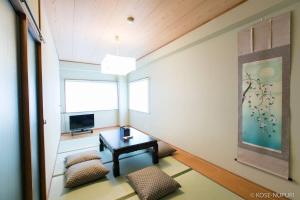 a room with a table and chairs and a television at bHOTEL Marumasa - Spacious next to PeacePark Family Condo Up to 13 P in Hiroshima