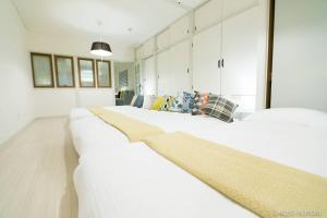 a row of white beds in a room at bHOTEL Marumasa - Spacious next to PeacePark Family Condo Up to 13 P in Hiroshima