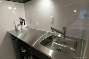 Una cocina con un fregadero de acero inoxidable en una cocina. en Origaminn 402 by b hotel - 5 mins PeacePark, en Hiroshima 26 fotos más