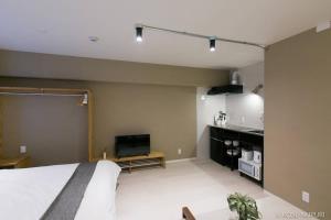 Un dormitorio con una cama y un televisor de pantalla plana. en Origaminn 402 by b hotel - 5 mins PeacePark, en Hiroshima