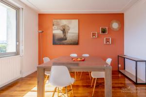 an orange dining room with a wooden table and white chairs at Rêveries au bord de l’Erdre in Nantes