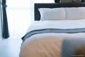 una cama blanca con cabecera negra y almohadas blancas en Origaminn 301 by b hotel - 5 mins Peace Park, en Hiroshima