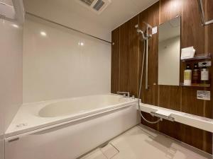 a bathroom with a white tub and a mirror at bHOTEL M's lea - Spacious Family apartment next to Peace Park in Hiroshima