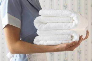 a woman holding a stack of white towels at bHOTEL Origaminn 301 - 5 mins Peace Park in Hiroshima