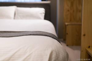 1 cama con sábanas y almohadas blancas en Origaminn 302 by b hotel - 5 mins PeacePark, en Hiroshima