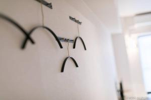 tres perchas negras colgadas en una pared en Origaminn 303 by b hotel - 5 mins PeacePark, en Hiroshima