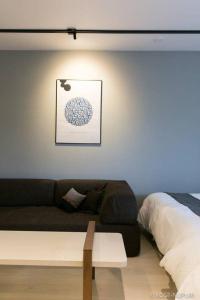 een woonkamer met een bank en een bed bij Origaminn 502 by b hotel - 5 mins PeacePark in Hiroshima