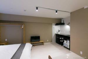 1 dormitorio con 1 cama y TV de pantalla plana en bHOTEL Origaminn 502 - 5 mins PeacePark en Hiroshima