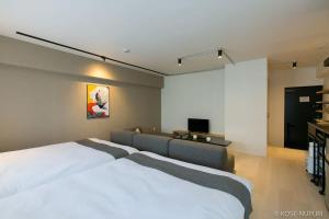 a bedroom with a bed and a couch and a tv at bHOTEL Origaminn 601 - 5 mins PeacePark in Hiroshima