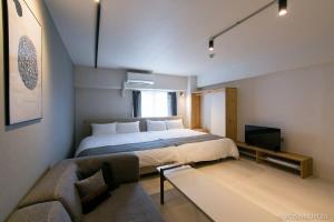 1 dormitorio con 1 cama grande y 1 sofá en bHOTEL Origaminn 702 - 5 mins PeacePark, en Hiroshima