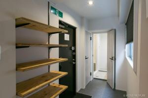 un corridoio con scaffali in legno e una porta di bHOTEL Origaminn 503 - 5 mins PeacePark a Hiroshima