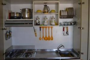 een keuken met een wastafel, een fornuis en keukengerei bij Holiday House Naxos in Giardini Naxos