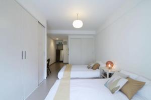 a white bedroom with two beds and a table at bHOTEL La-Shante - 5 mins walk to the PeacePark & 2BR 10 ppl #101 in Hiroshima