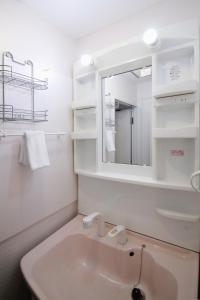 Baño blanco con lavabo y espejo en bHOTEL La-Shante - 5 mins walk to the PeacePark & 2BR 10 ppl #101, en Hiroshima