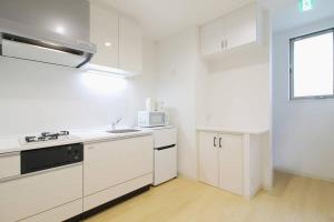 een witte keuken met een spoelbak en een magnetron bij b hotel Ball Park - 2mins walk Baseball 5mins walk Hiroshima Sta in Hiroshima