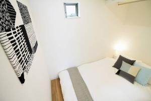 een slaapkamer met een wit bed met zwart-witte kussens bij b hotel Ball Park - 2mins walk Baseball 5mins walk Hiroshima Sta in Hiroshima