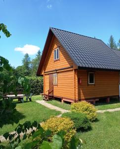 a wooden cabin with a bench in a yard at Domek 667-798-007 in Polańczyk