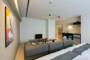 a living room with a couch and a tv in it at bHOTEL Origaminn 701 - 5 mins PeacePark in Hiroshima