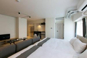 a bedroom with a large white bed and a couch at bHOTEL Origaminn 701 - 5 mins PeacePark in Hiroshima